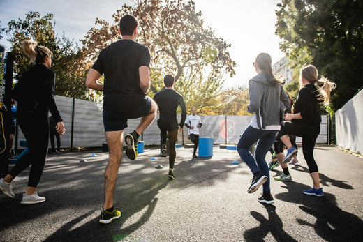 Ein Bild einer Gruppe von Personen, die gemeinsam im Freien trainieren, mit einem Fokus auf Lauftechnik-Übungen. Die Szene vermittelt Dynamik, Teamgeist und Bewegung.