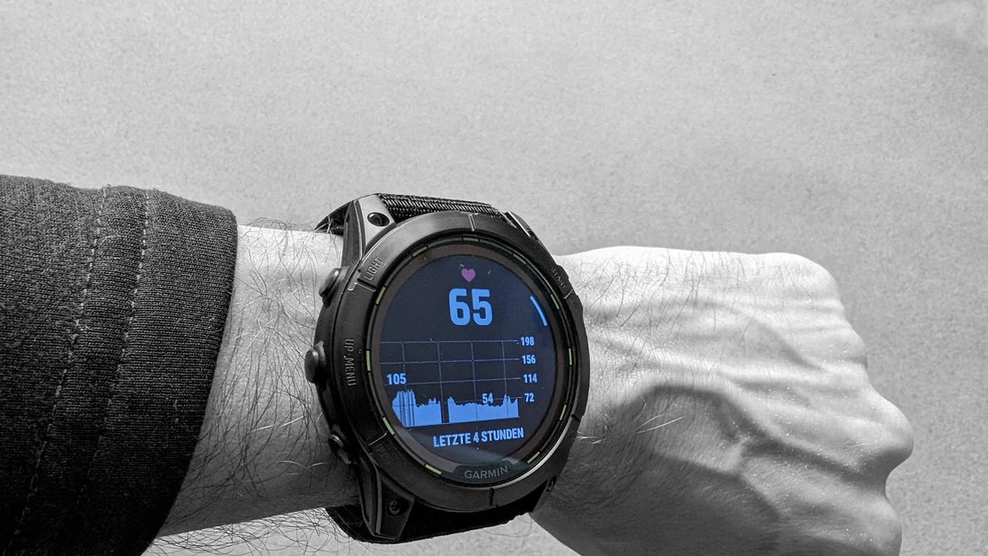 Nahaufnahme einer Smartwatch am Handgelenk, die eine Herzfrequenz von 65 anzeigt, zusammen mit einem grafischen Verlauf der Herzfrequenz über die letzten 4 Stunden.